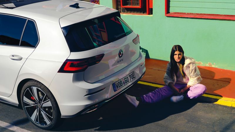 VW Golf GTE parkerad vid en trottoar. En kvinna sitter bakom bilen.