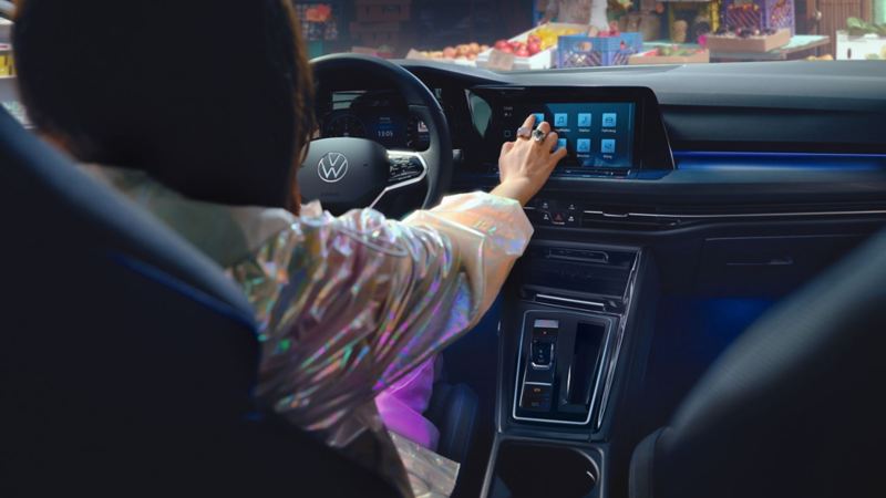 Intérieur de la VW Golf GTE, vue du tableau de bord, une femme utilise les fonctionnalités de l'écran tactile