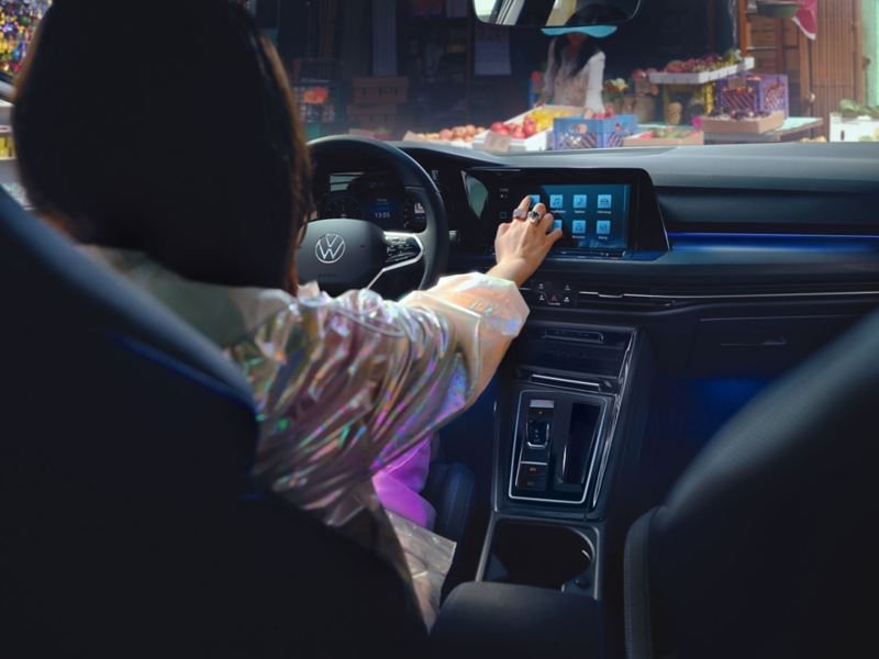 Interiør af en VW Golf GTE, hvor en kvinde styrer touchskærmen med den ene hånd