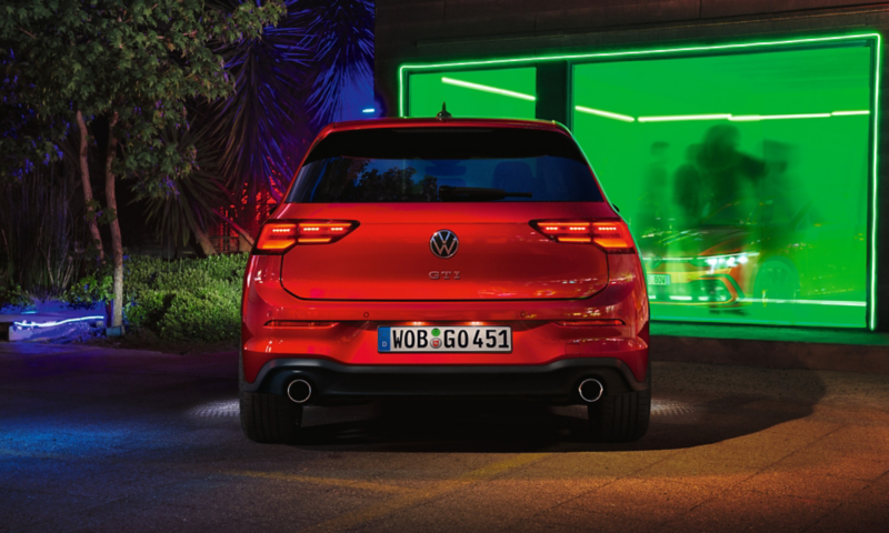 VW Golf GTI in red, rear view, parked in front of a club