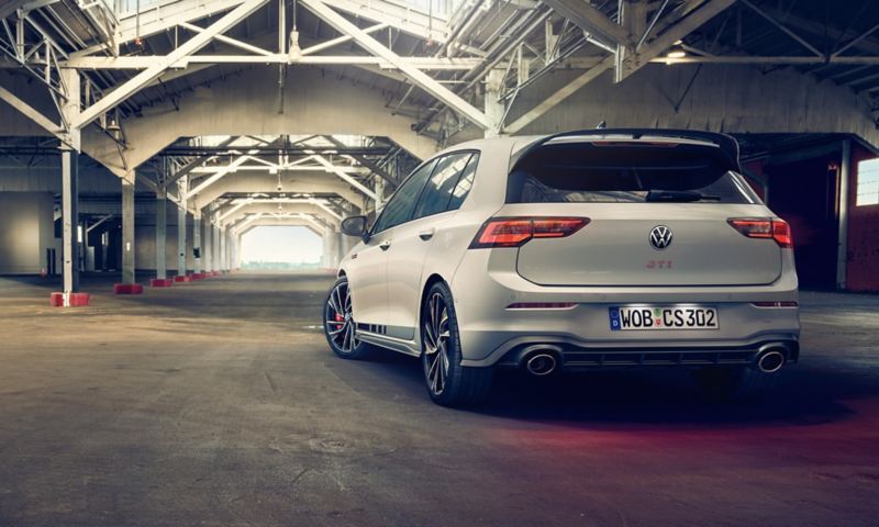 Weißer VW Golf GTI Clubsport steht in einer leeren Fabrikhalle. Ansicht des Hecks. 