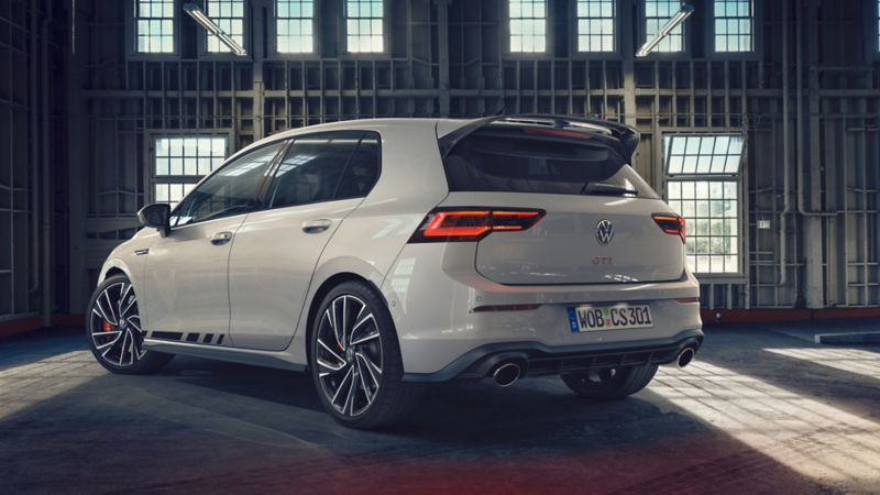 VW Golf GTI Clubsport in white in front of a window front in an empty factory building. Side view of the rear and side. 