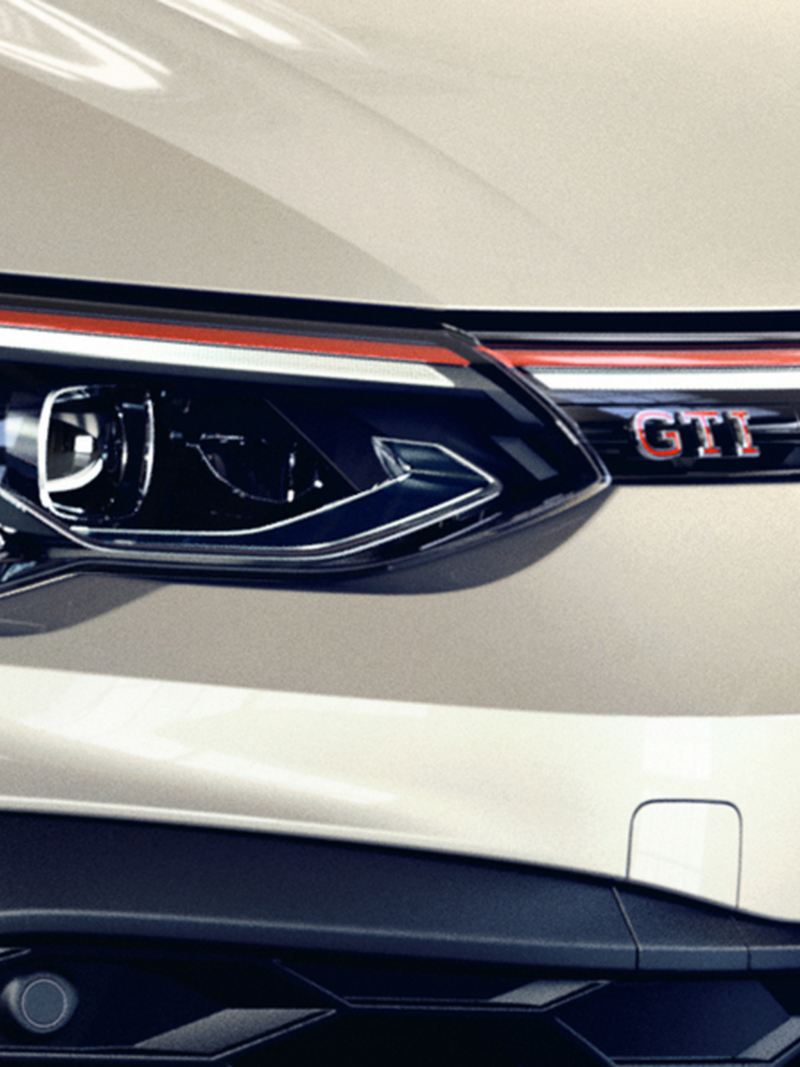Λεπτομερής άποψη του μπροστινού μέρους ενός λευκού VW Golf GTI Clubsport με εστίαση σε έναν προβολέα LED και στην επιγραφή GTI στη μάσκα ψυγείου. 