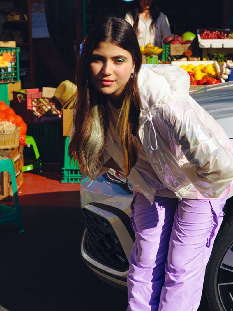 Detailed view of the bonnet of the VW Golf GTE next to a market stall with fruit, a young woman standing in front of it.