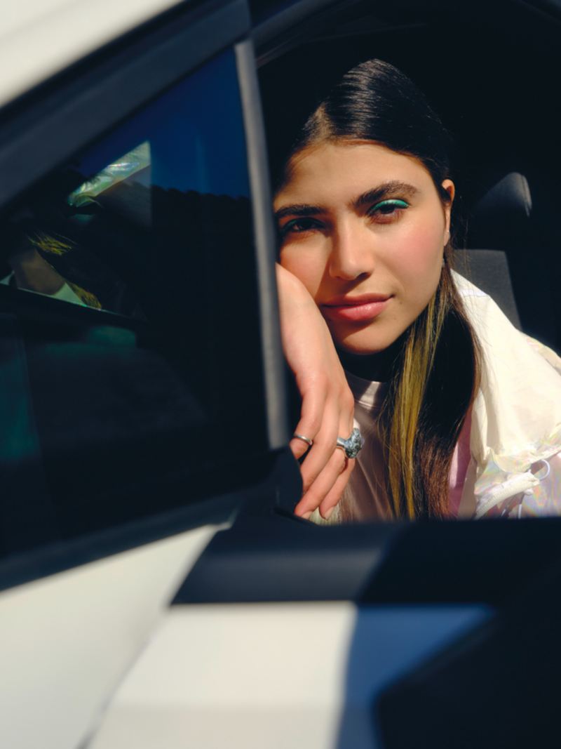 VW Golf GTE en blanc, regarde une jeune femme assise au volant au-delà du rétroviseur 