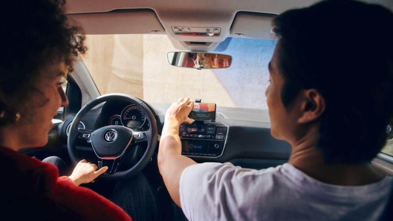 Passagerarna i en stillastående Volkswagen up! sätter fast en smartphone i hållaren.