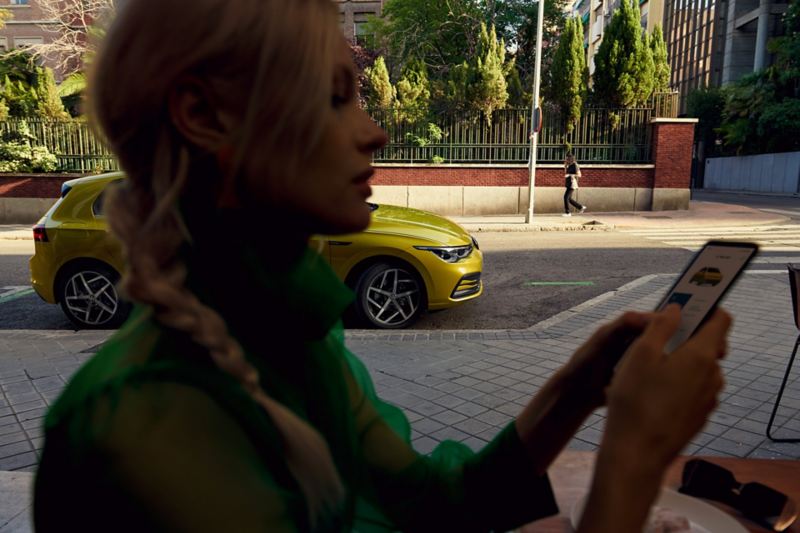 Mujer utilizando la aplicación Volkswagen en un teléfono móvil
