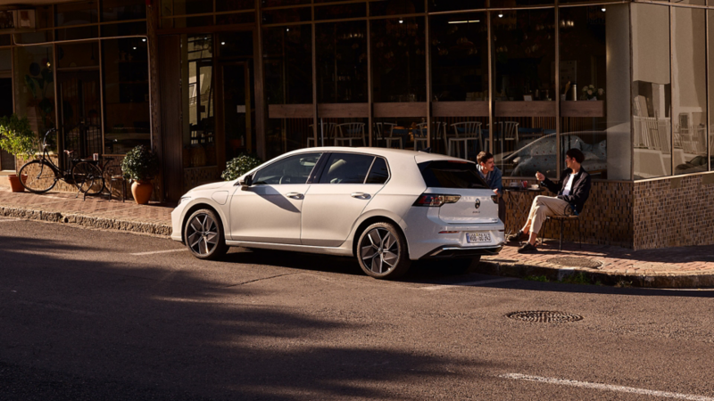 Weißer VW Golf parkt seitlich vor einem Restaurant