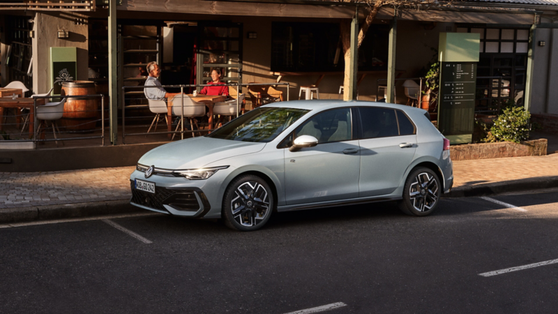 Une Golf R-Line grise de profil, garée devant un restaurant.