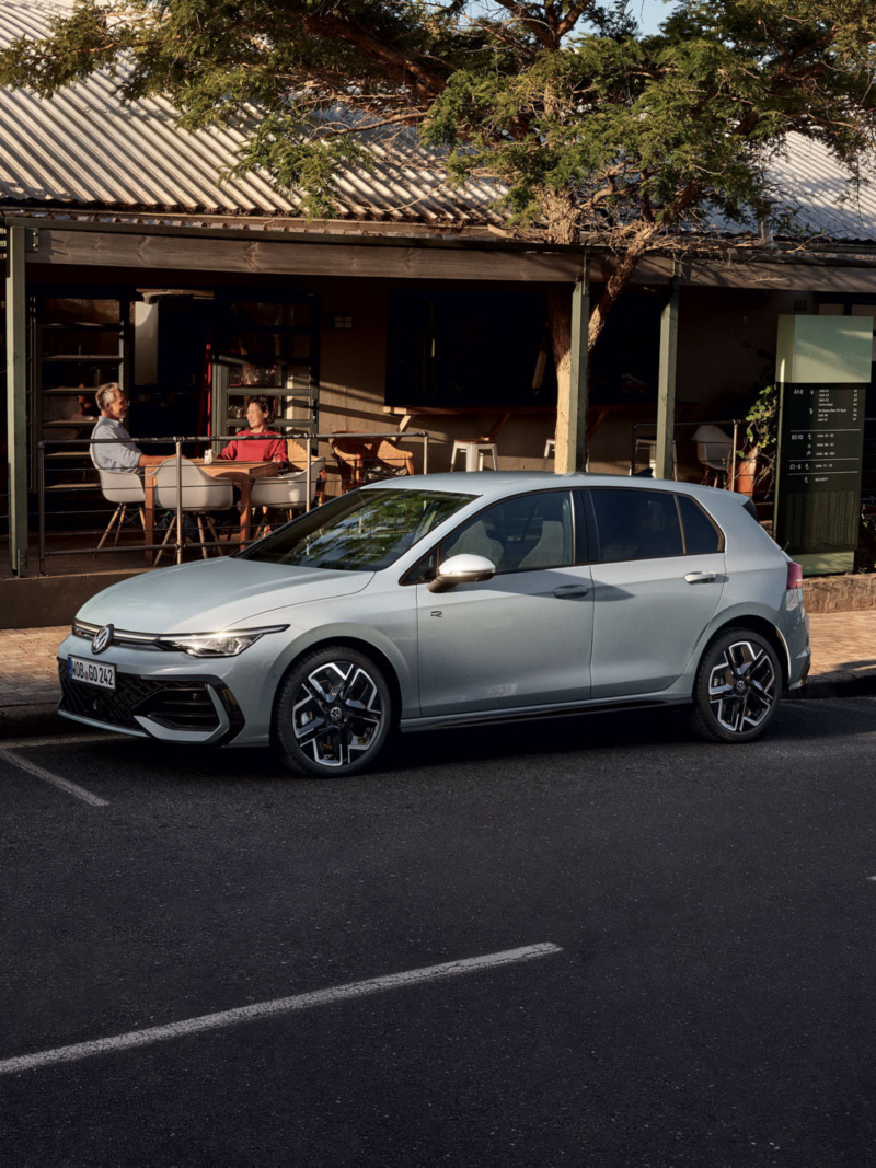 Une Golf R-Line grise de profil, garée devant un restaurant.