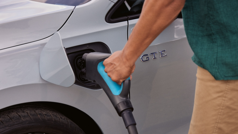 Person plugging in a Golf GTE to charge