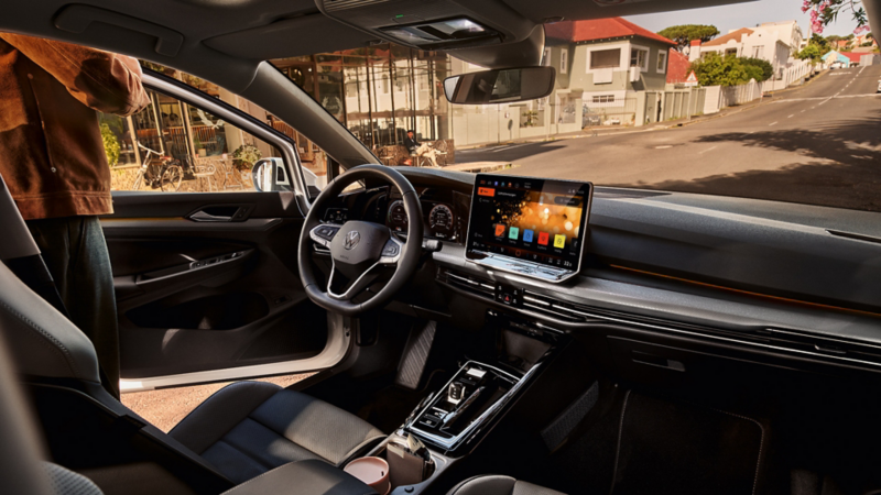 Interior of the VW Golf parked beside a café with the driver's side door open