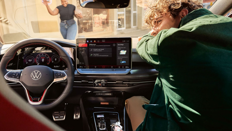 Une personne est assise sur le siège passager d’une VW Golf GTI.