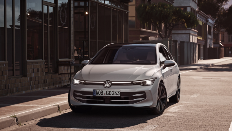 A white VW Golf parked in front of a café