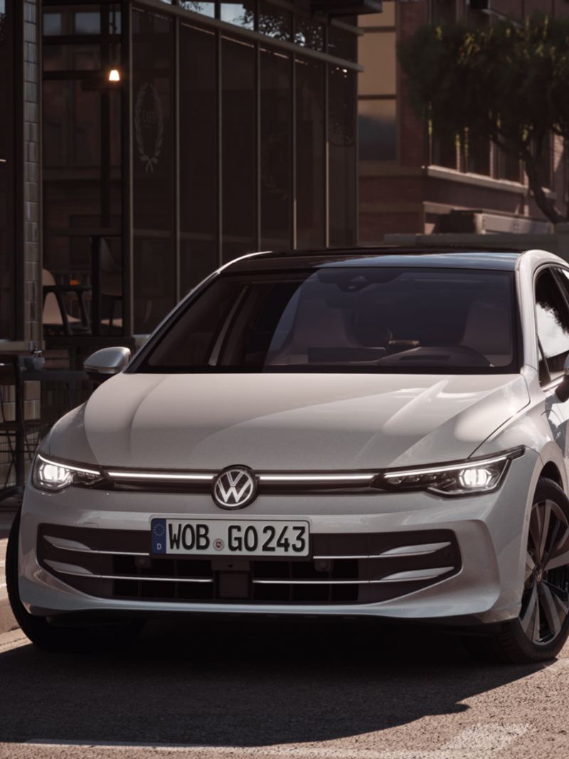 Side view of a moving white VW Golf eHybrid.