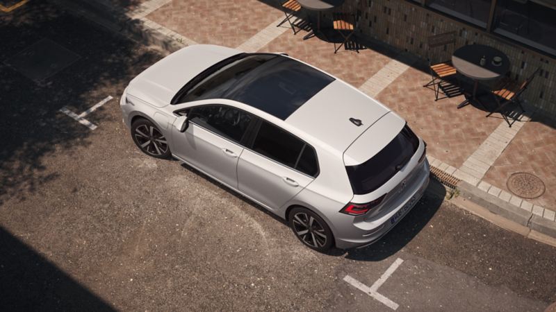 "Bovenaanzicht van een witte VW Golf, met focus op het panoramische kantel-/schuifdak. "