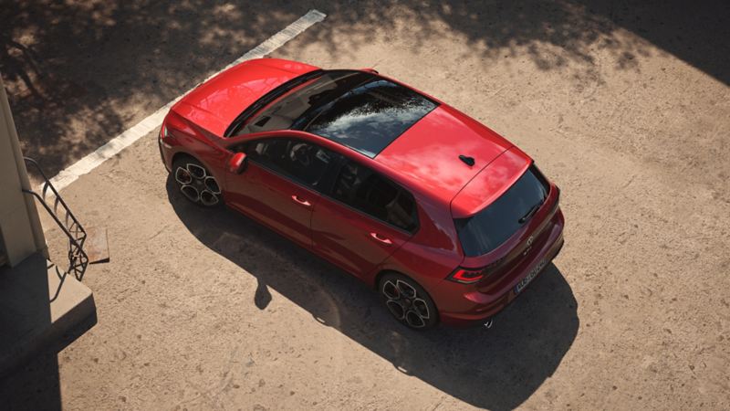 Vue de dessus d’une VW Golf GTI rouge mettant l’accent sur le toit panoramique relevable et coulissant.