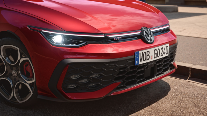 Une VW Golf GTI blanche roule avec l’assistant de feux de route activé.