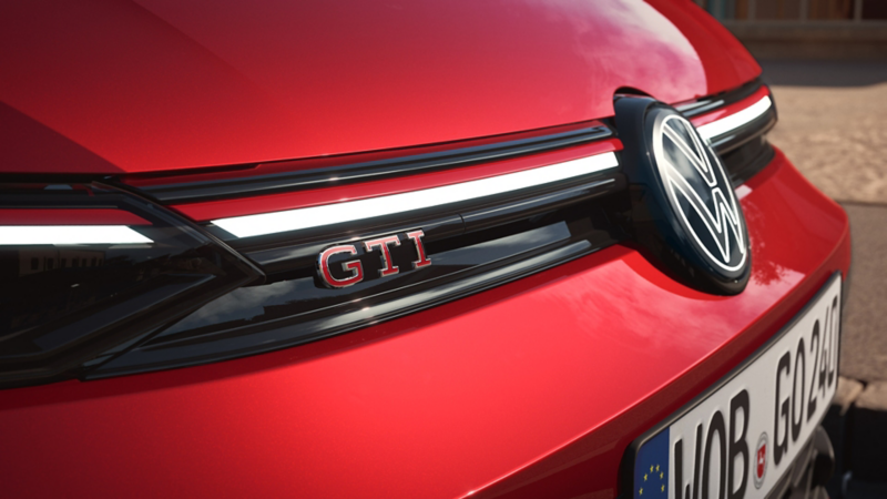 "Et blik på fronten af en rød VW Golf GTI med fokus på GTI-logoet. "