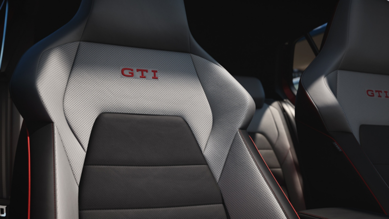 Vordersitze im VW Golf GTI mit GTI-Logo und roten Ziernähten.
