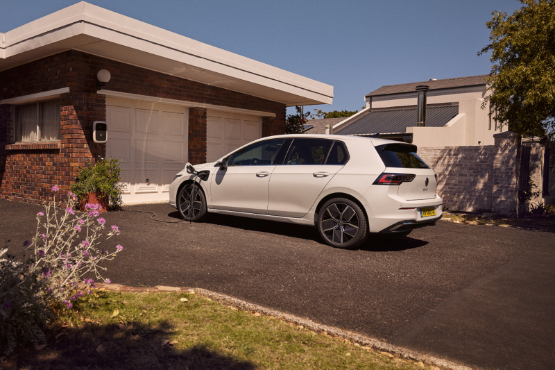 Witte Volkswagen Golf plug-in hybride staat op een oprit, hij wordt opgeladen