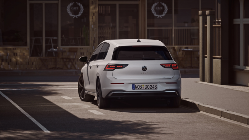 Woman sitting in front of a VW Tiguan charging at a wallbox.