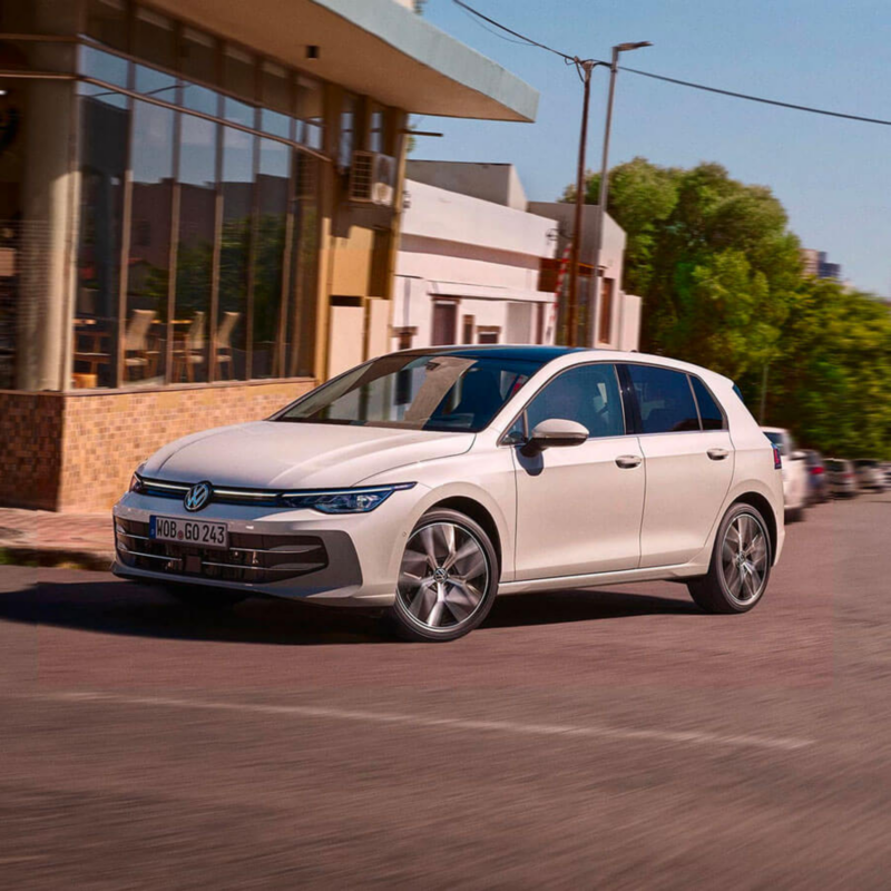 Une VW Golf tourne à un croisement, en passant devant un restaurant.