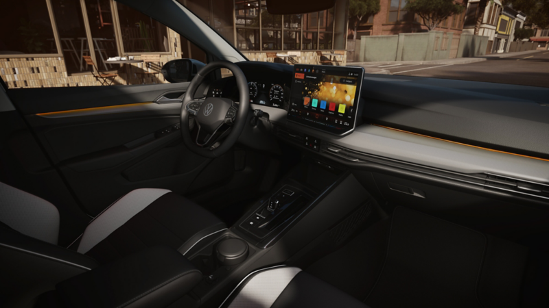 Interior of the Golf with a view from the passenger seat through the windscreen onto the road. A young man stands at the open driver's door.