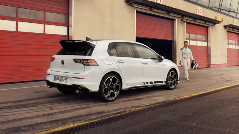 Rear shot of a white VW Golf GTI Clubsport with a racing driver walking in front of it