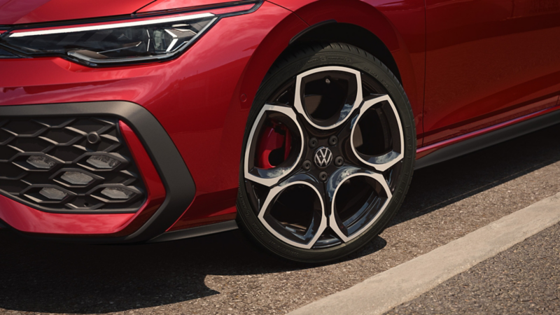 Blick auf die Vordersitze eines roten VW Golf GTI bei geöffneter Fahrertür. Eine Frau schaut in das Auto hinein.