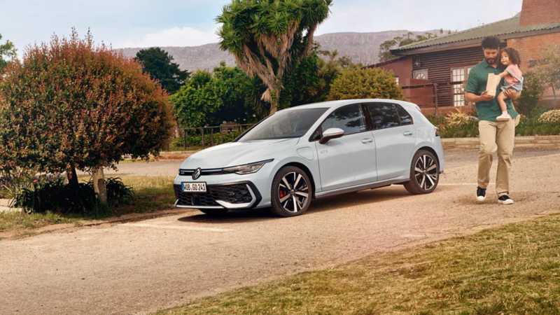 Eine Person steht neben einem weißen VW Golf GTE.