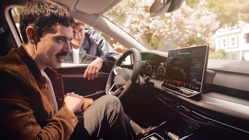 Een man achter het stuur van een Volkswagen praat maakt gebruik van de spraakassistent