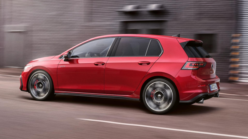 Ein roter VW Golf GTI fährt vor einer Lagerhalle entlang.