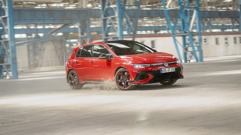 Roter VW Golf GTI EDITION 50 fährt eine Kurve in einer Werkhalle.