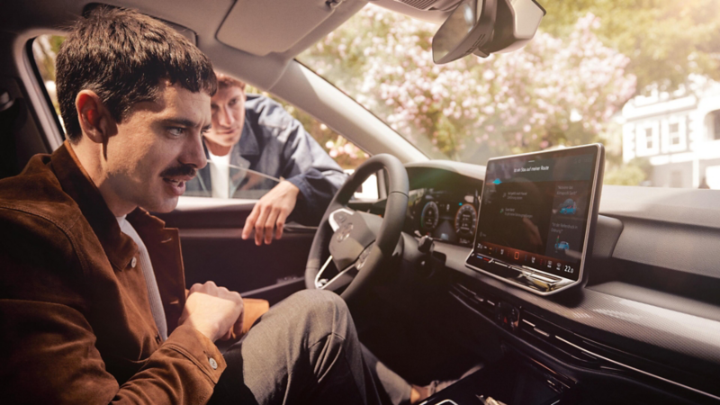 Zwei Männer schauen auf das Display eines VW.