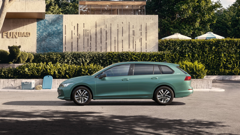 Ein grüner VW Golf Variant parkt vor einem Freibad.
