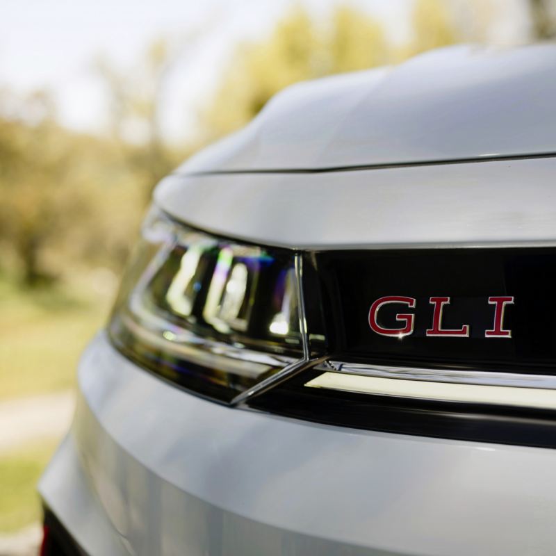 Close-up of the front badge on a Volkswagen Jetta GLI 2025, with the letters "GLI' in red against a chrome background.