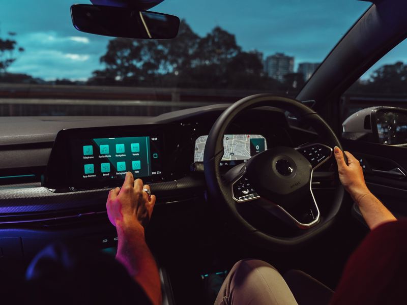 Wide image of Volkswagen Golf interior in the dark, lit by neon lights and ambient lighting.