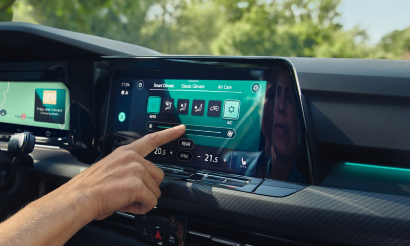 Ansicht des Digital Cockpit Pro mit Farbdisplay im VW Golf Variant. Im Display die Anzeige der Klimaanlage, eine Hand bedient die Touch-Fläche.