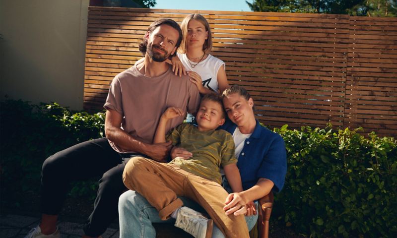 Une famille de quatre personnes assise dans le jardin sous le soleil.