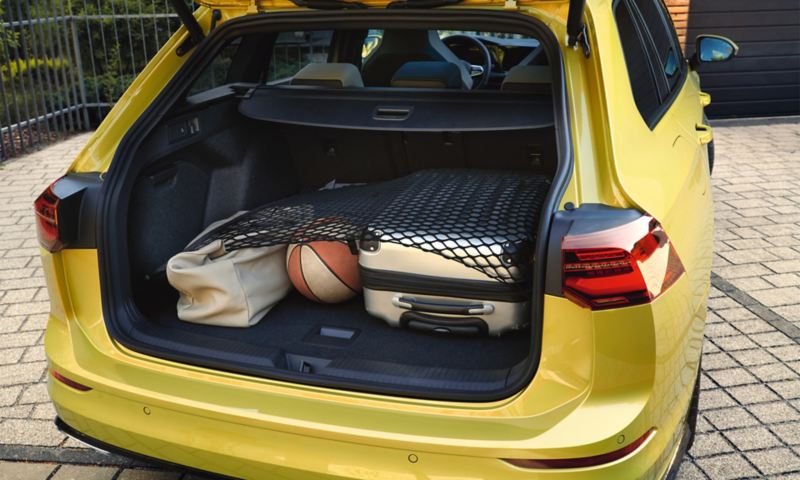 Golf 8 Variant eTSI ibrida parcheggiata con bagagliaio aperto. Al suo interno una valigia, un borsone e una palla da basket.