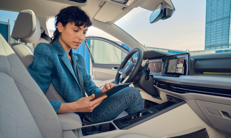 Une femme utilise sa tablette à l'intérieur de sa Golf, via Streaming & Connect.