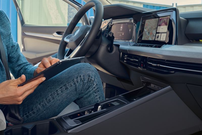 Άποψη από το κάθισμα του συνοδηγού μιας γυναίκας στο κάθισμα του οδηγού στο VW Golf. Χρησιμοποιεί το ενσωματωμένο WLAN-Hotspot με ένα tablet.