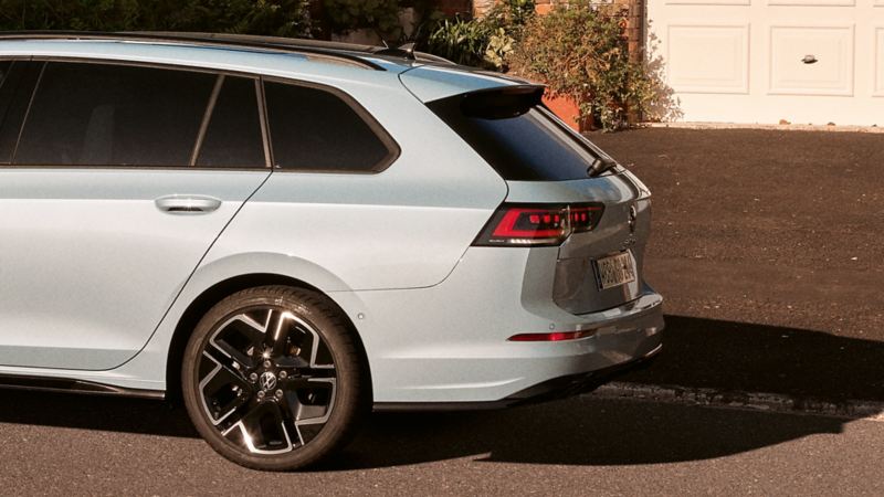 "Une VW Golf Variant blanche est stationnée sur une allée devant une porte de garage. La moitié arrière de la voiture est visible. "