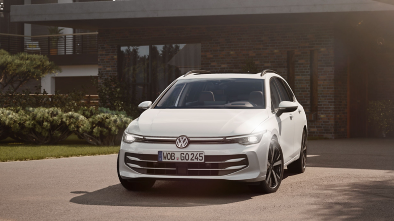 Ein weißer VW Golf Variant parkt vor einem Haus.