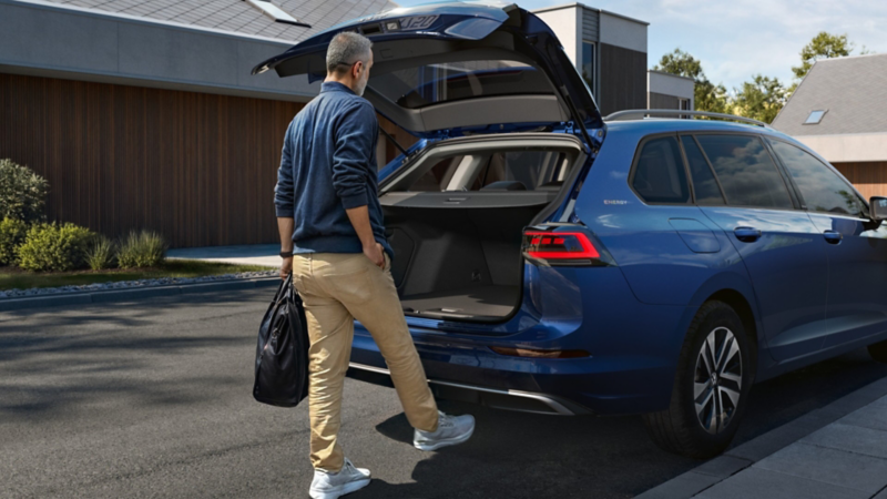 Ein Mann schließt durch eine Fussbewegung die Heckklappe eines VW Golf Variant ENERGY.