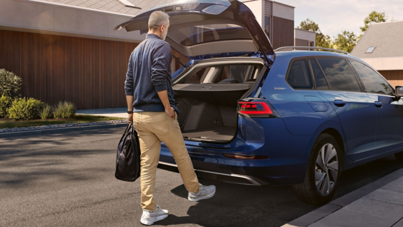 Ein Mann schließt durch eine Fussbewegung die Heckklappe eines VW Golf Variant ENERGY.