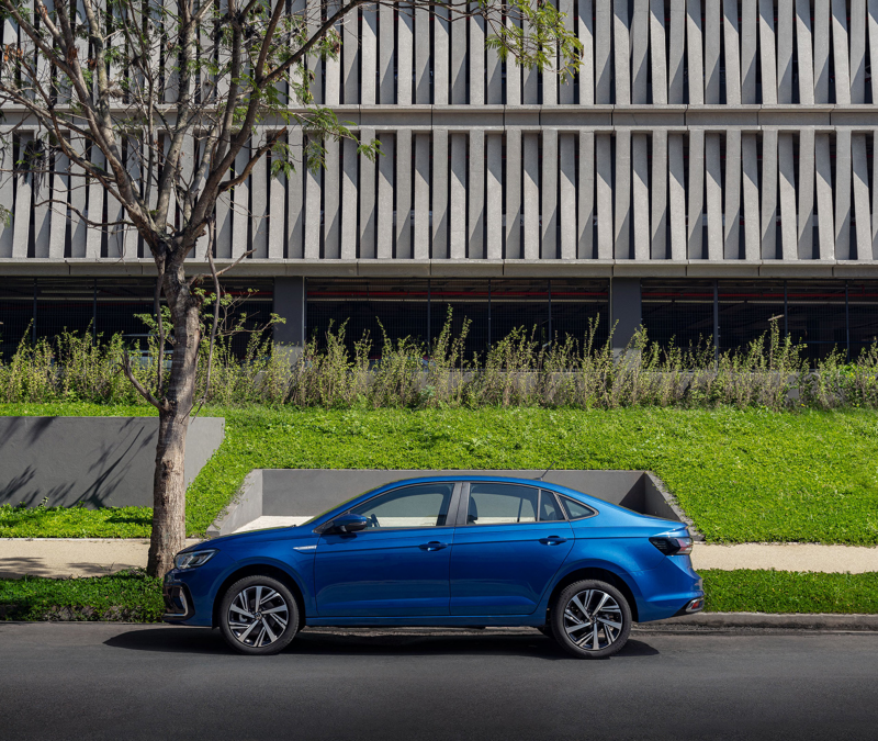 Volkswagen Virtus 2024 azul estacionado frente a un edificio moderno, destacando su diseño elegante y características avanzadas para un sedán compacto-mediano.