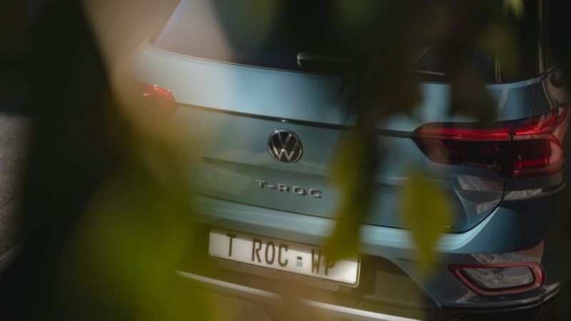 A white Volkswagen Tiguan Allspace is parked in a meadow, view of the rear. 