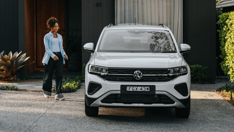 Woman standing walking to her Volkswagen T-Cross.